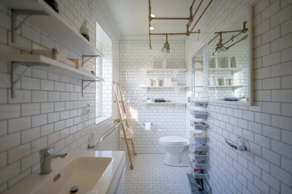 A photo of a modern, bright bathroom with white subway tiles. It features creative bathroom organization and storage solutions