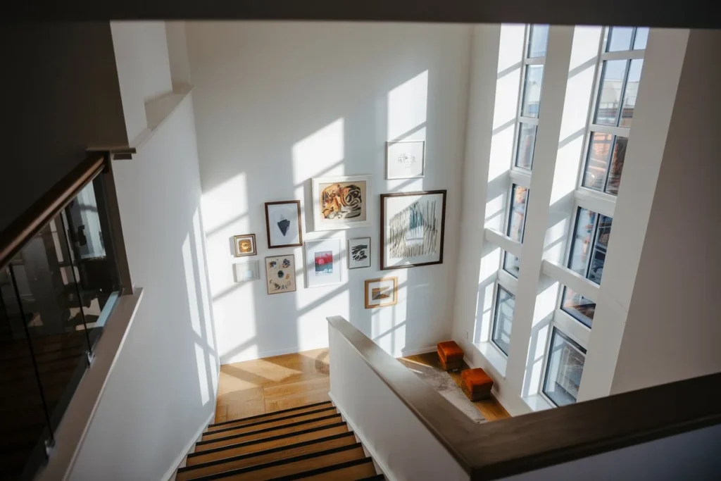 Staircase decor idea with white walls featuring a stunning gallery wall arrangement and natural light streaming through nearby windows